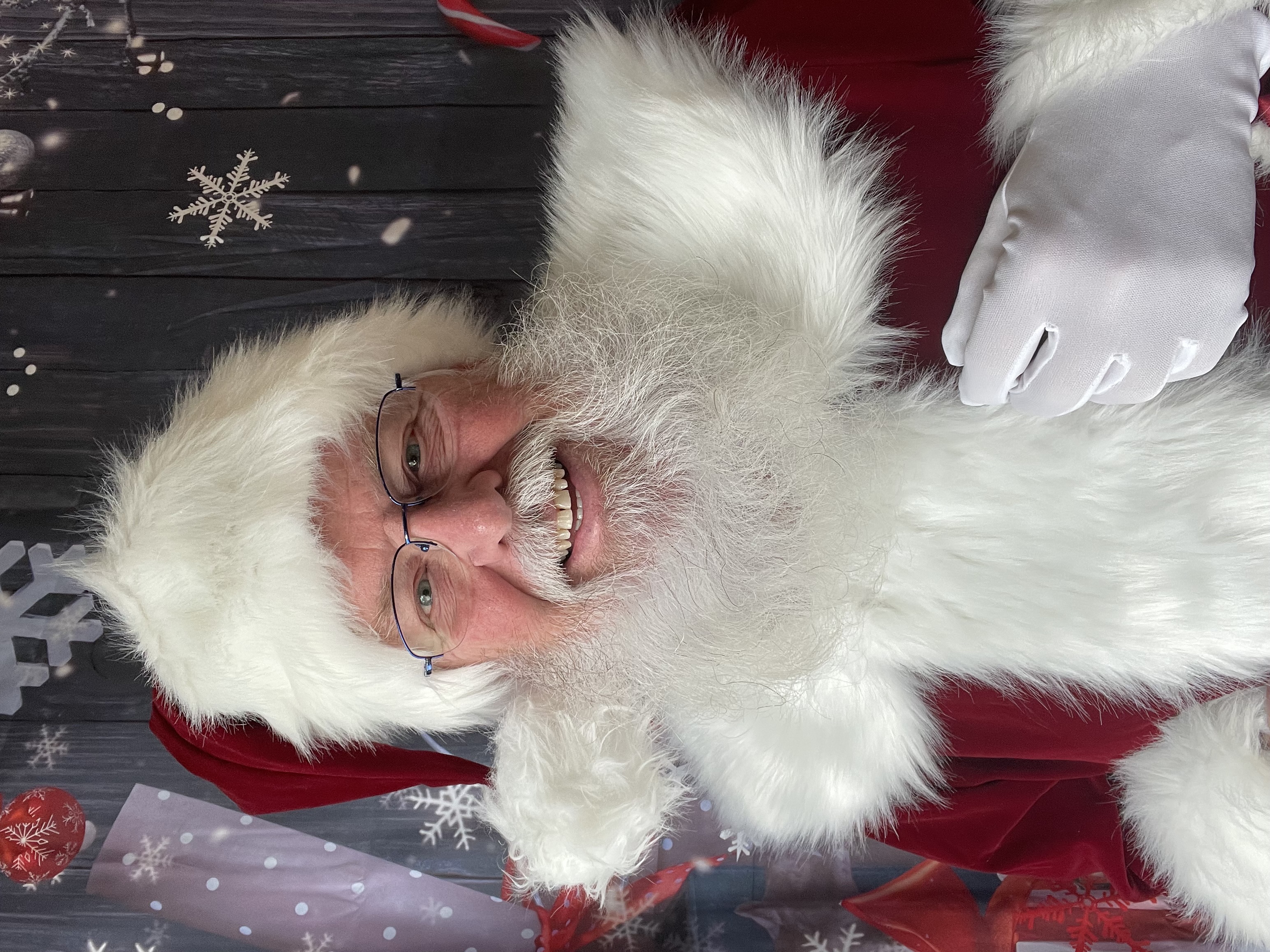Clean headshot of Santa Ricky with warm smile and bright eyes, classic red cap, studio light.