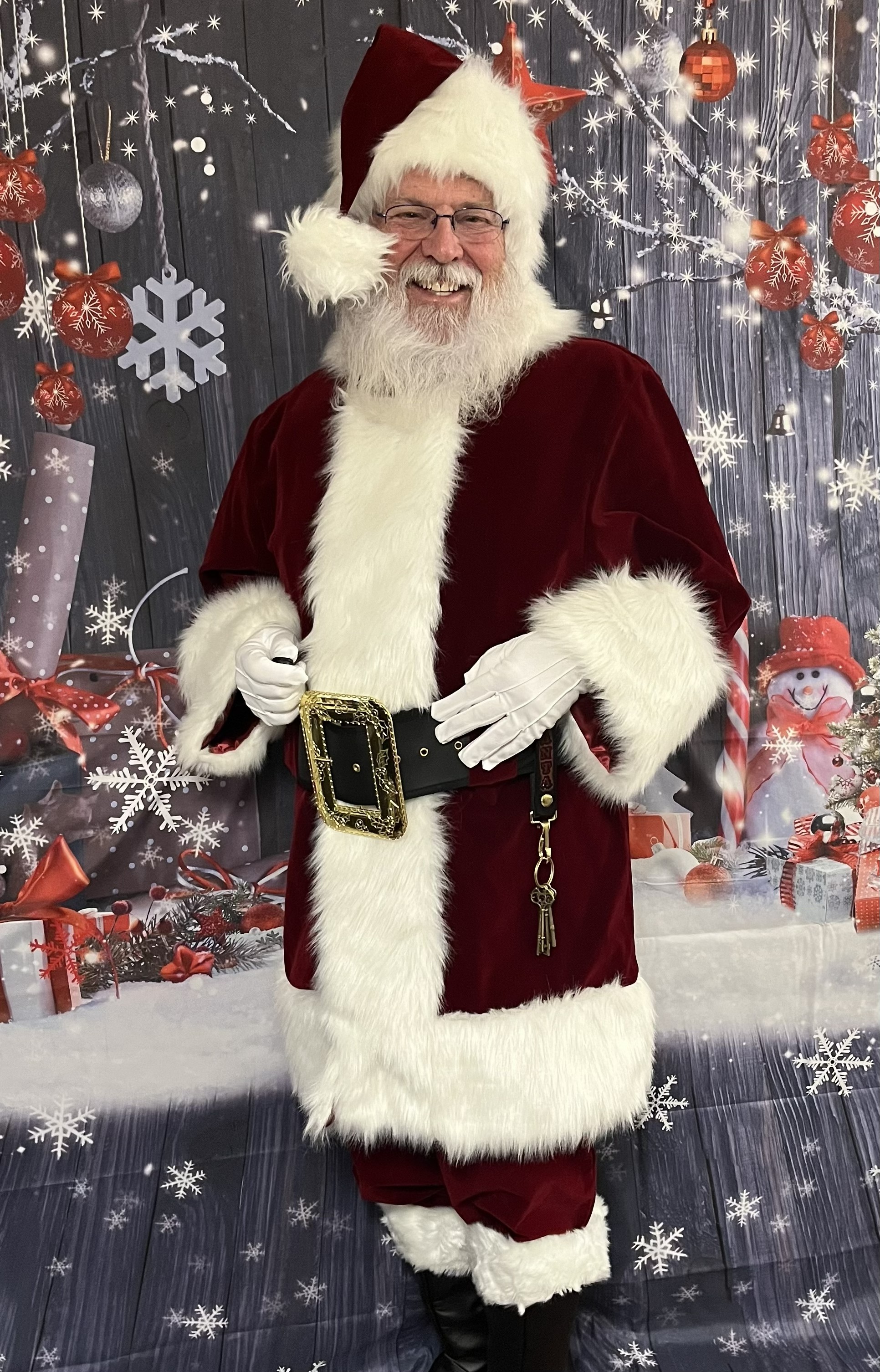 Warm, close headshot of Santa Ricky smiling with twinkling eyes and classic red cap.